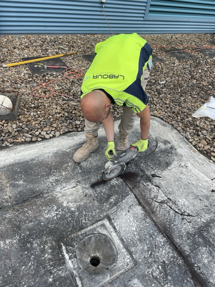 Worker wearing a safety vest and squatting on a concrete floor